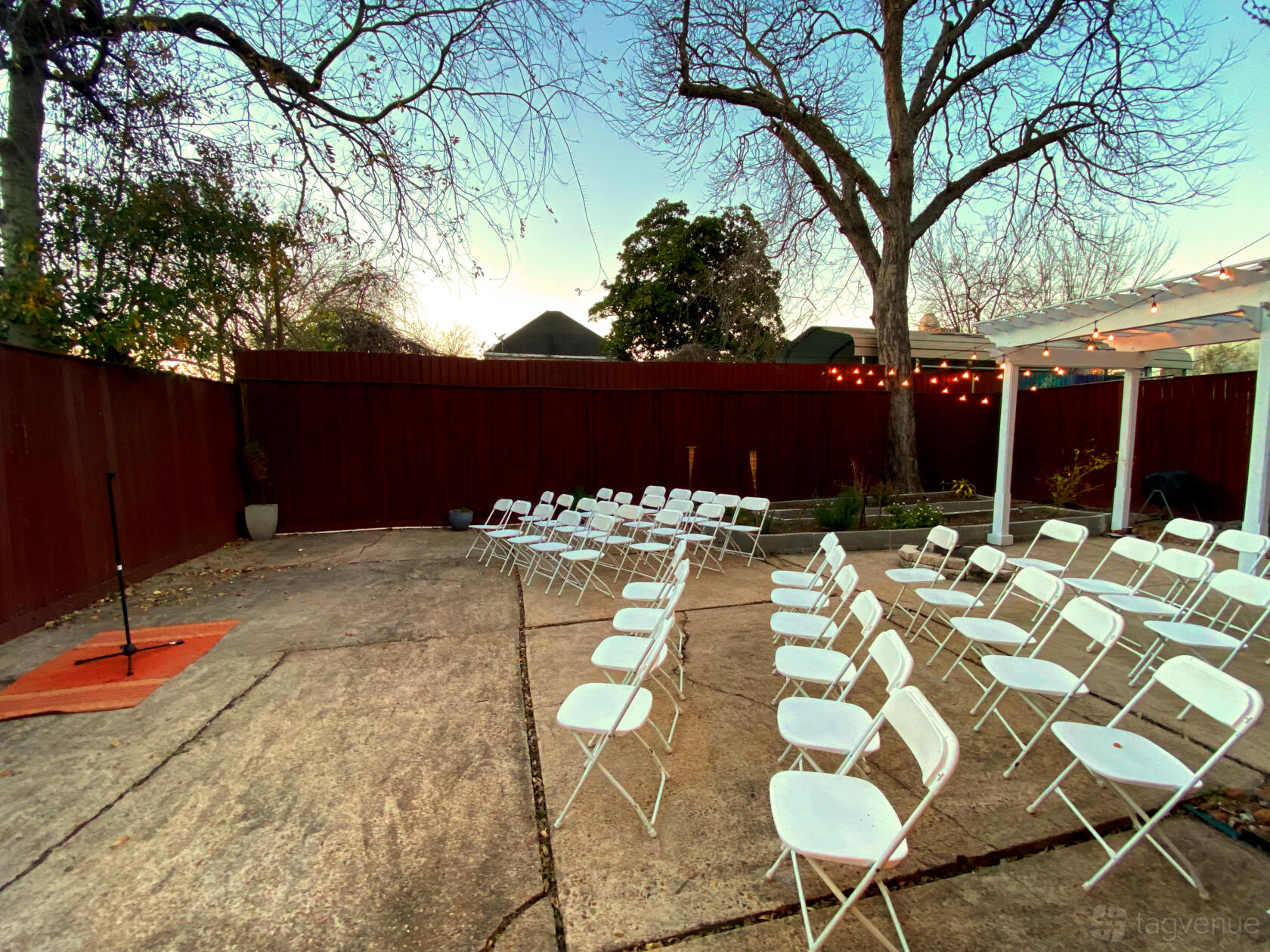 An outdoor studio courtyard with white folding chairs, string lights, and a small stage at Wonderlikewander.