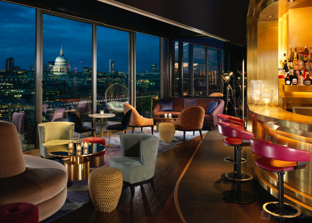 A hotel lounge with floor-to-ceiling windows, colorful velvet chairs, and a gold bar at Sea Containers Hotel's 12th Knot.