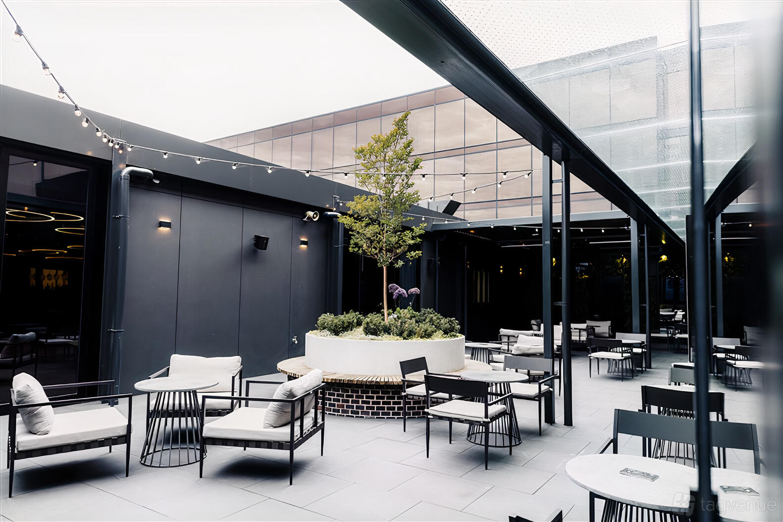 A hotel terrace with outdoor seating, string lights, and a central planter with a small tree at Mercure Melbourne Doncaster.