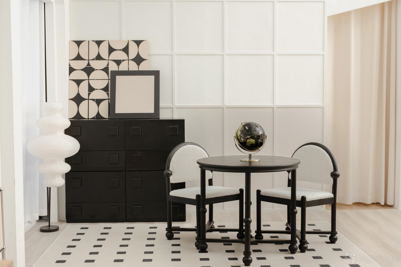 A photo studio with a round table, two chairs, geometric wall panels, and black storage drawers at Our Studio Space.