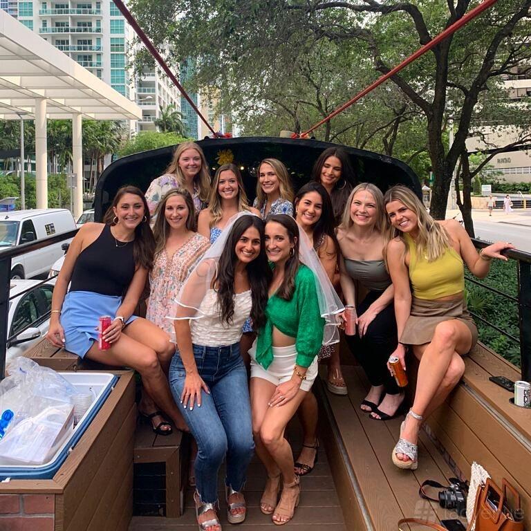 A party bus with open-air seating, wooden bench seats, and city street views at Rumbatours Miami.