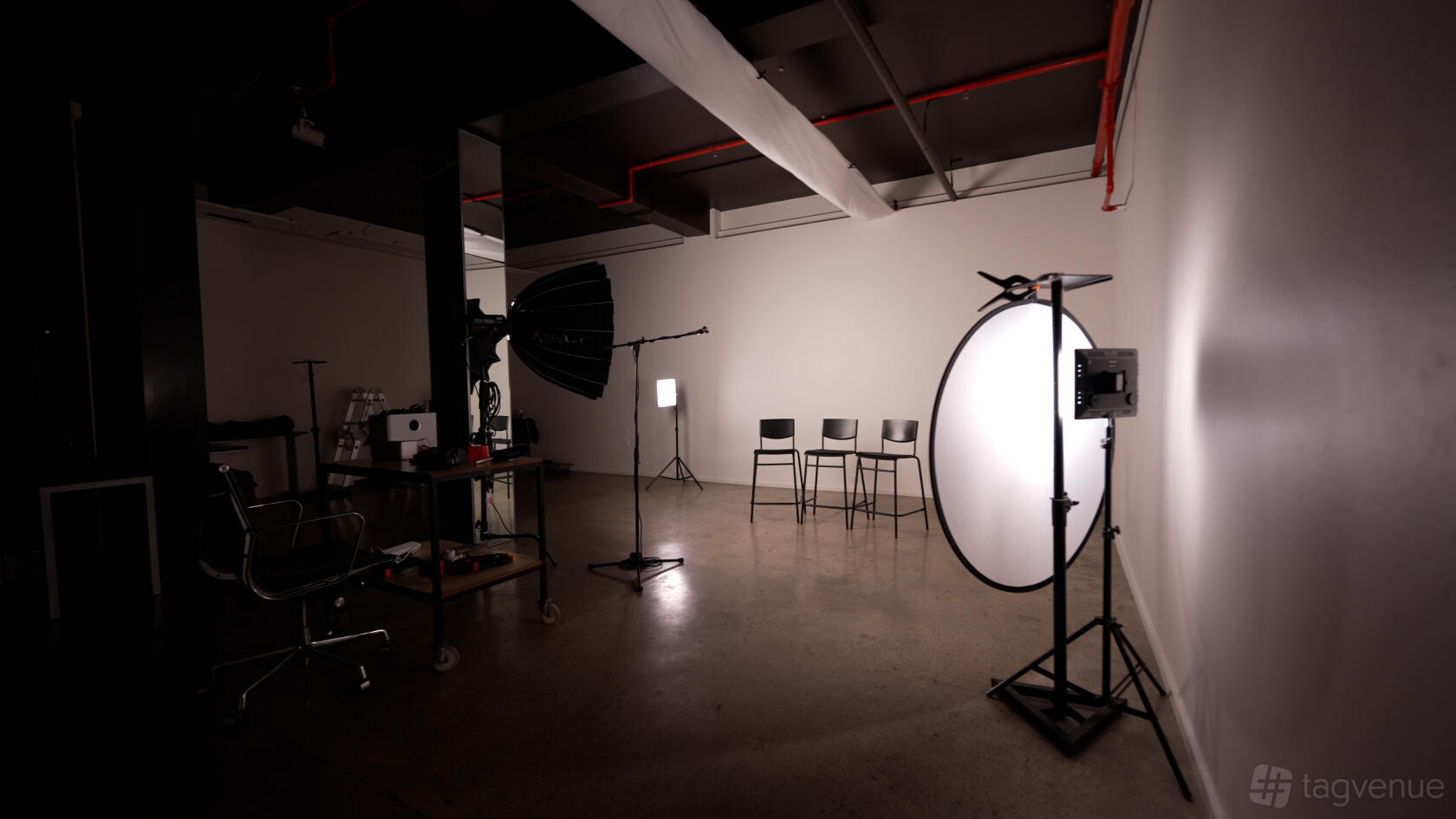 A photo studio with white walls, studio lights, backdrop, and stools set up for a shoot at Scroll Stop Studios.