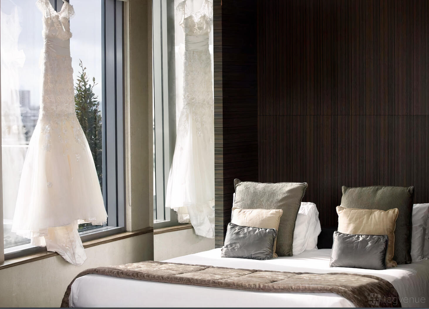An event space in a hotel with floor-to-ceiling windows, dark wood paneling, and a bed with decorative pillows at Leonardo Royal London St Paul's.