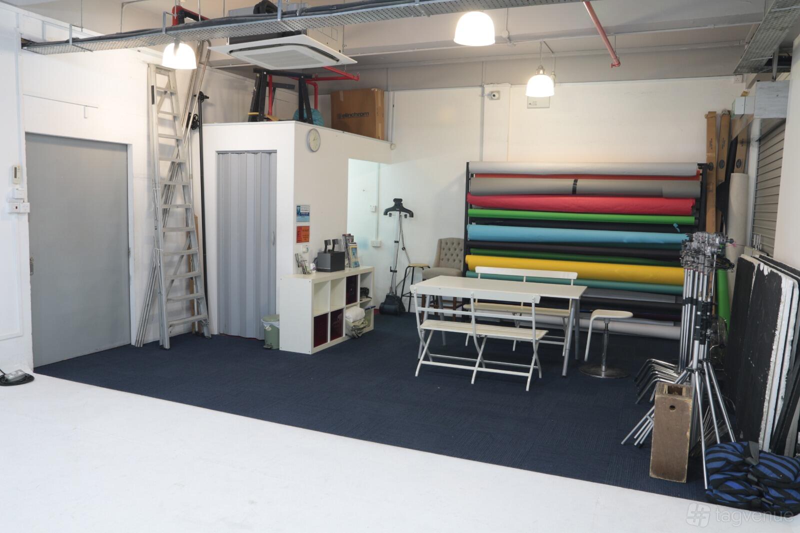 A photo studio with seamless backdrop rolls, folding tables with chairs, and studio equipment at Camwerkz Pte Ltd.