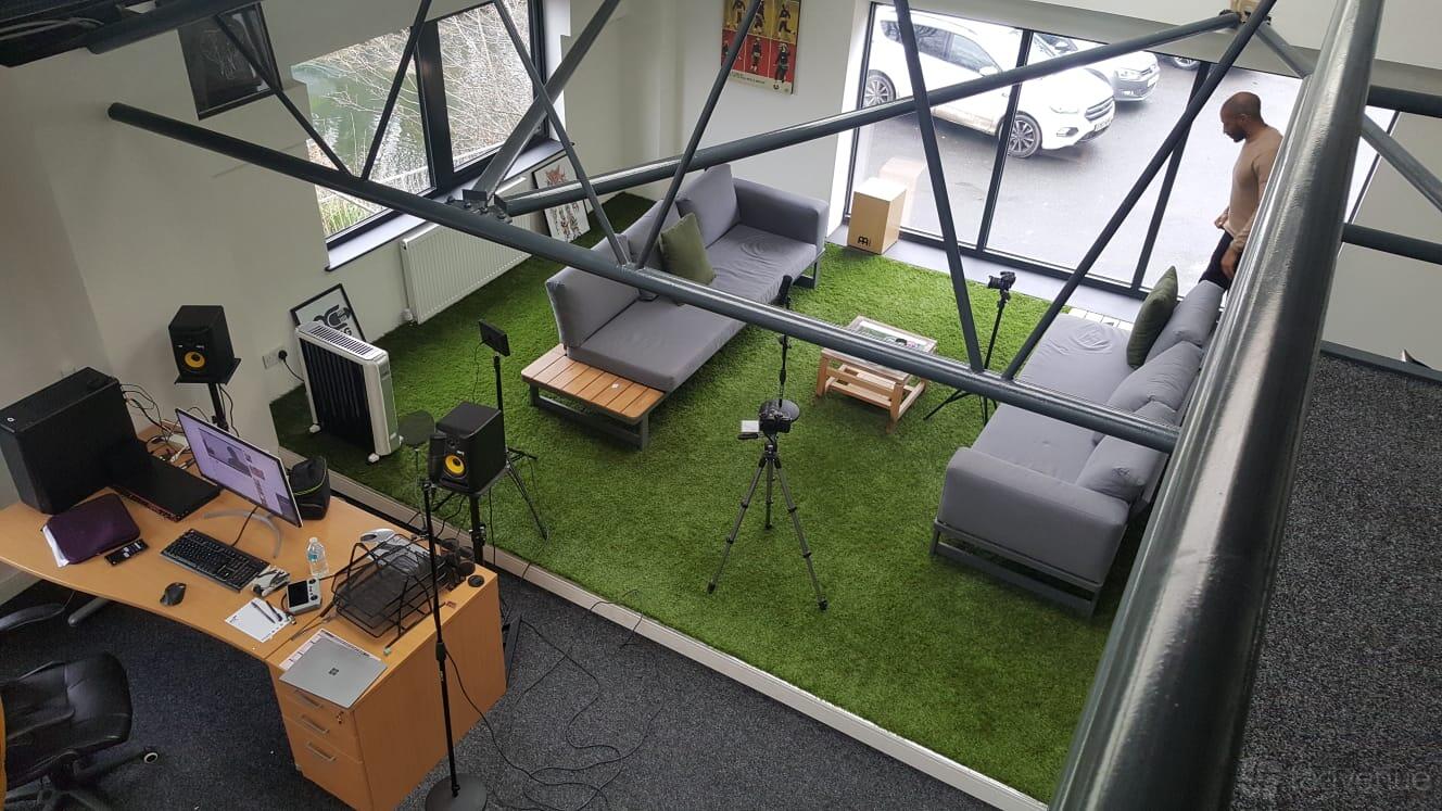 A recording studio with artificial grass flooring, couches, studio monitors, and a workstation at Making Change Studios.