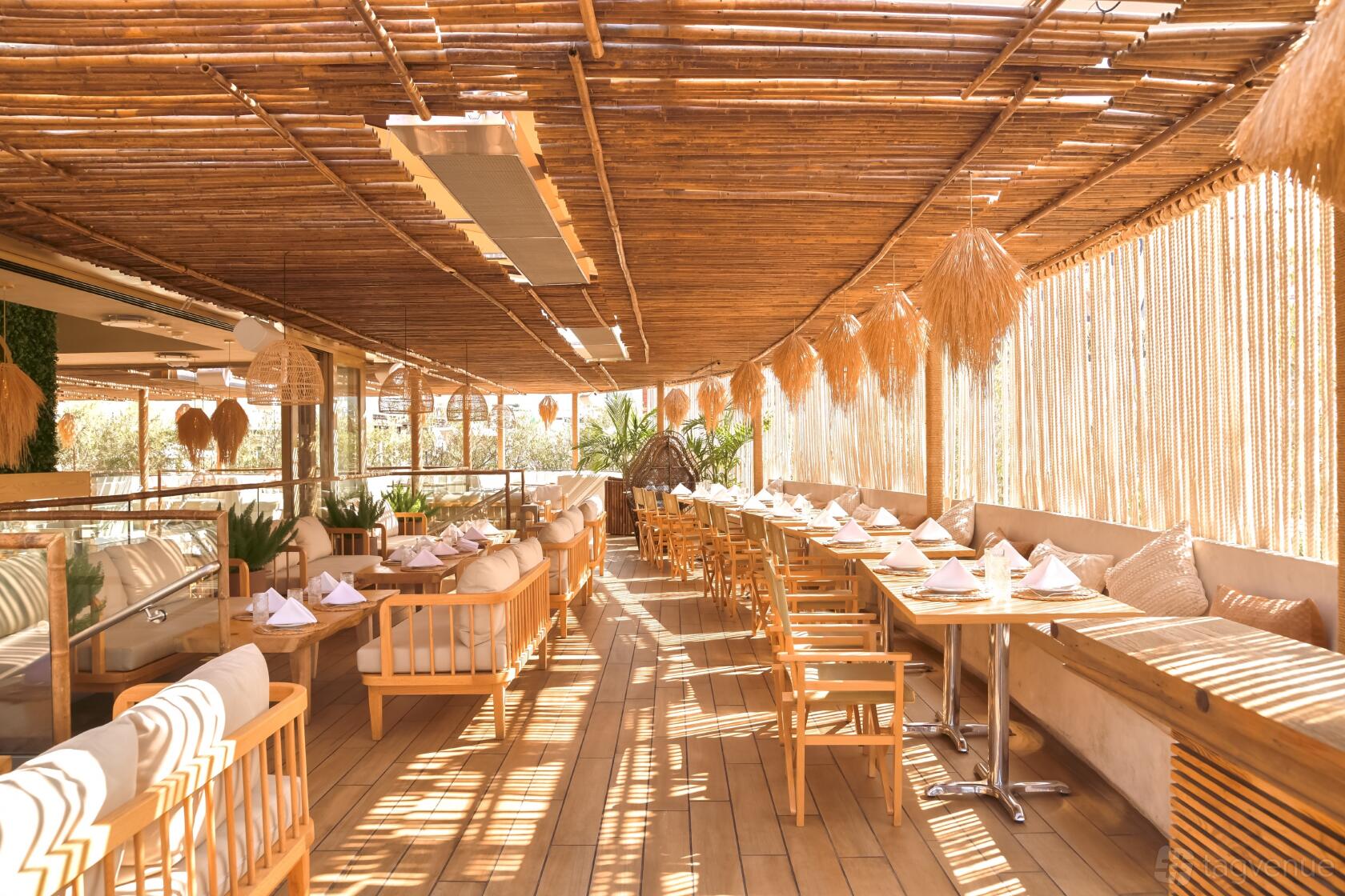 An event space in a restaurant with bamboo ceiling, wooden chairs, cushioned benches, and natural lighting at LouLou.