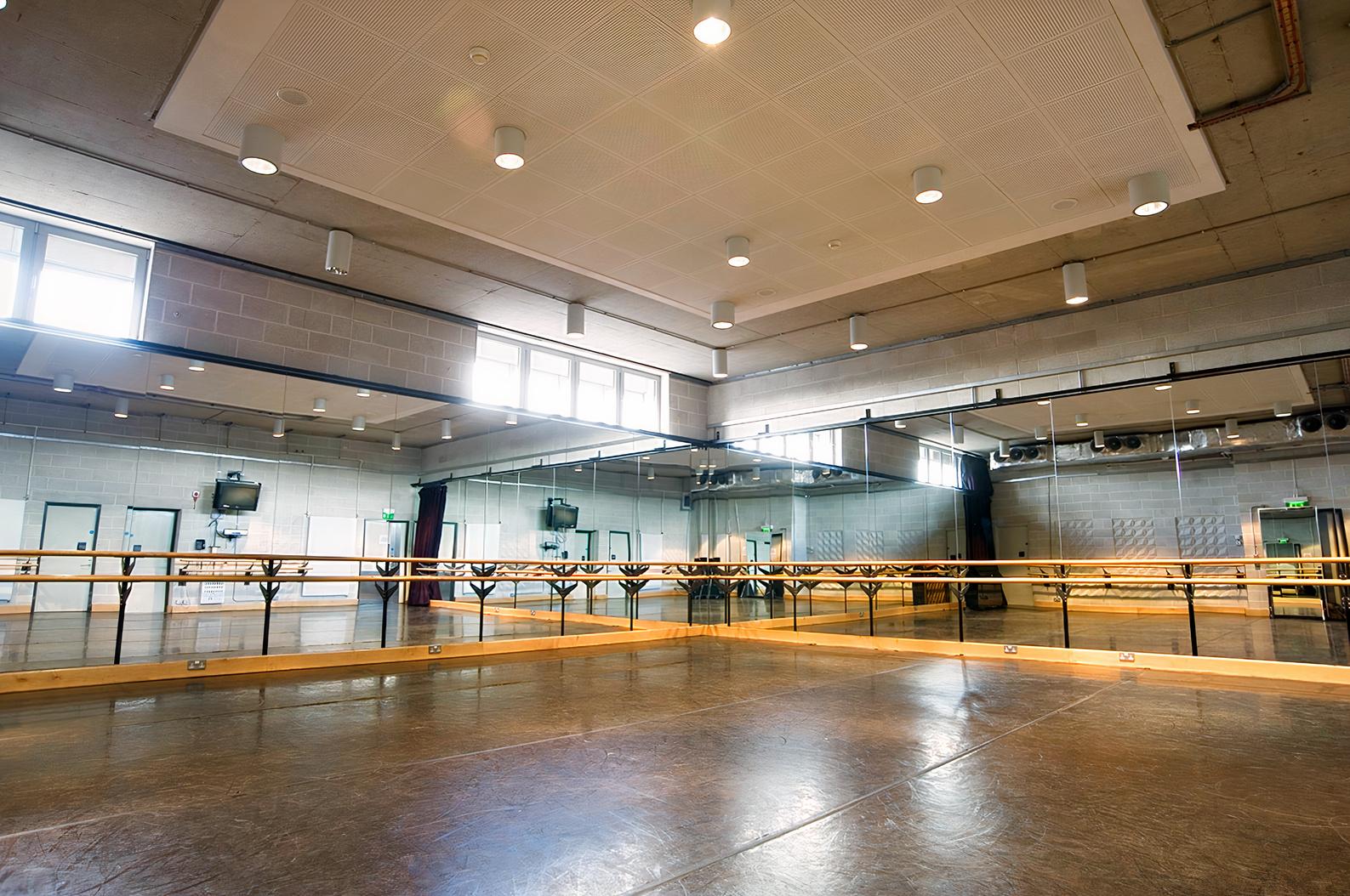 A dance studio with mirrored walls, ballet barres, and wooden flooring at Sadler's Wells.
