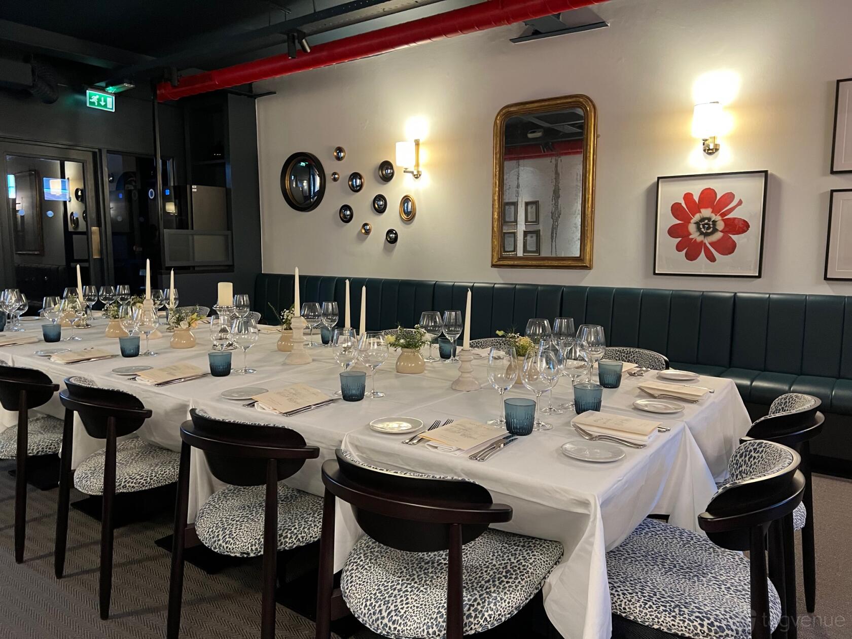 A private dining room with a long table set for guests, patterned chairs, and wall art at Manicomio Chelsea Restaurant.
