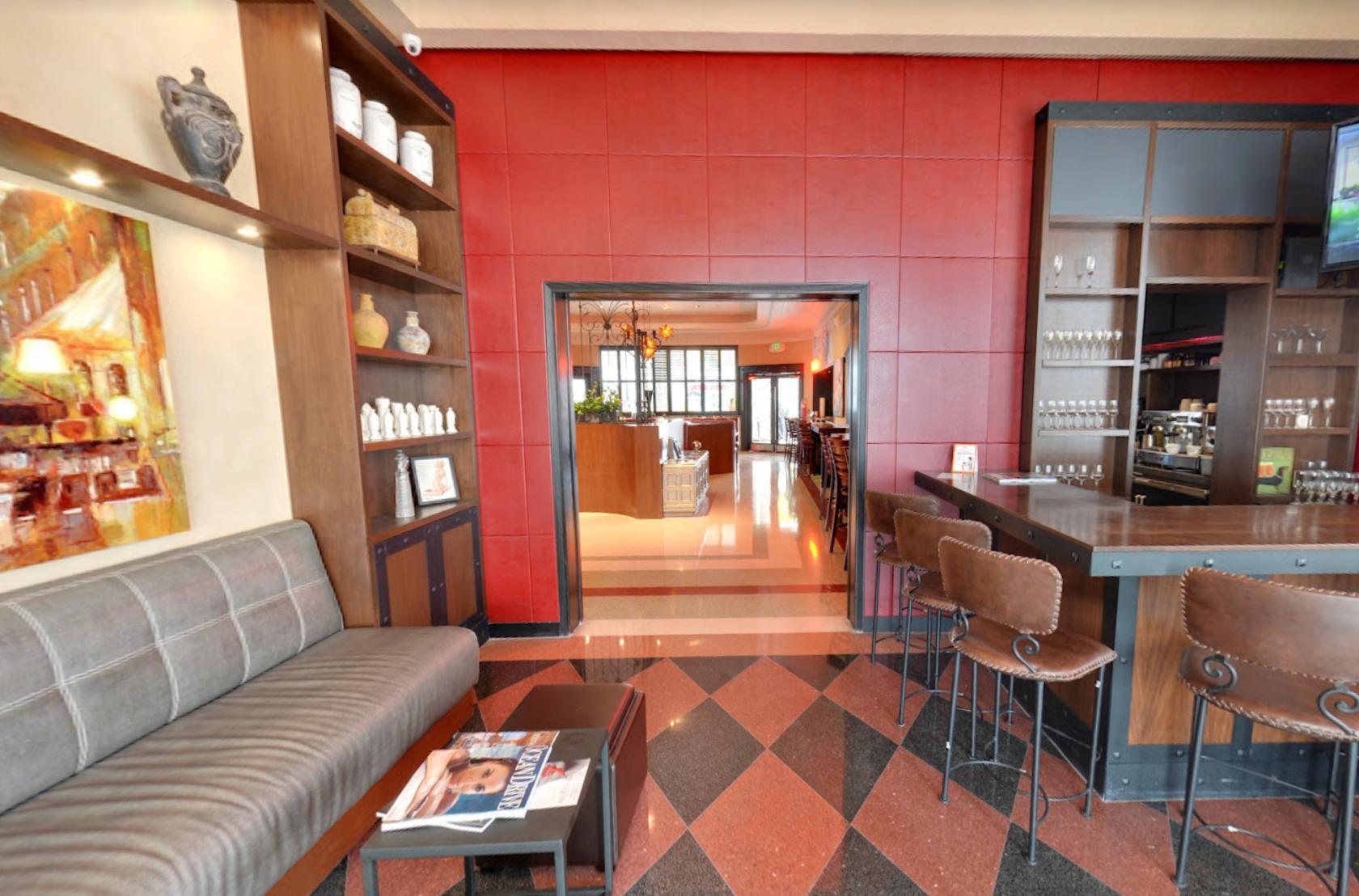 A dining room with red paneled walls, upholstered benches, bar stools, and open shelving at Naked Taco.