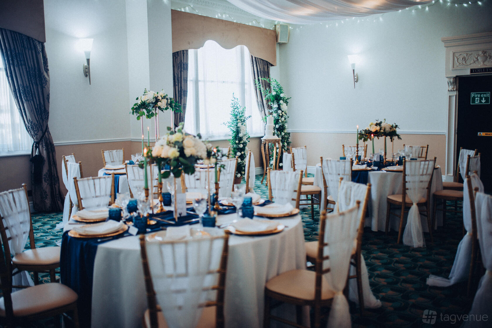 An event space with round tables, white chairs, navy table runners, and floral centerpieces at New Continental Hotel.