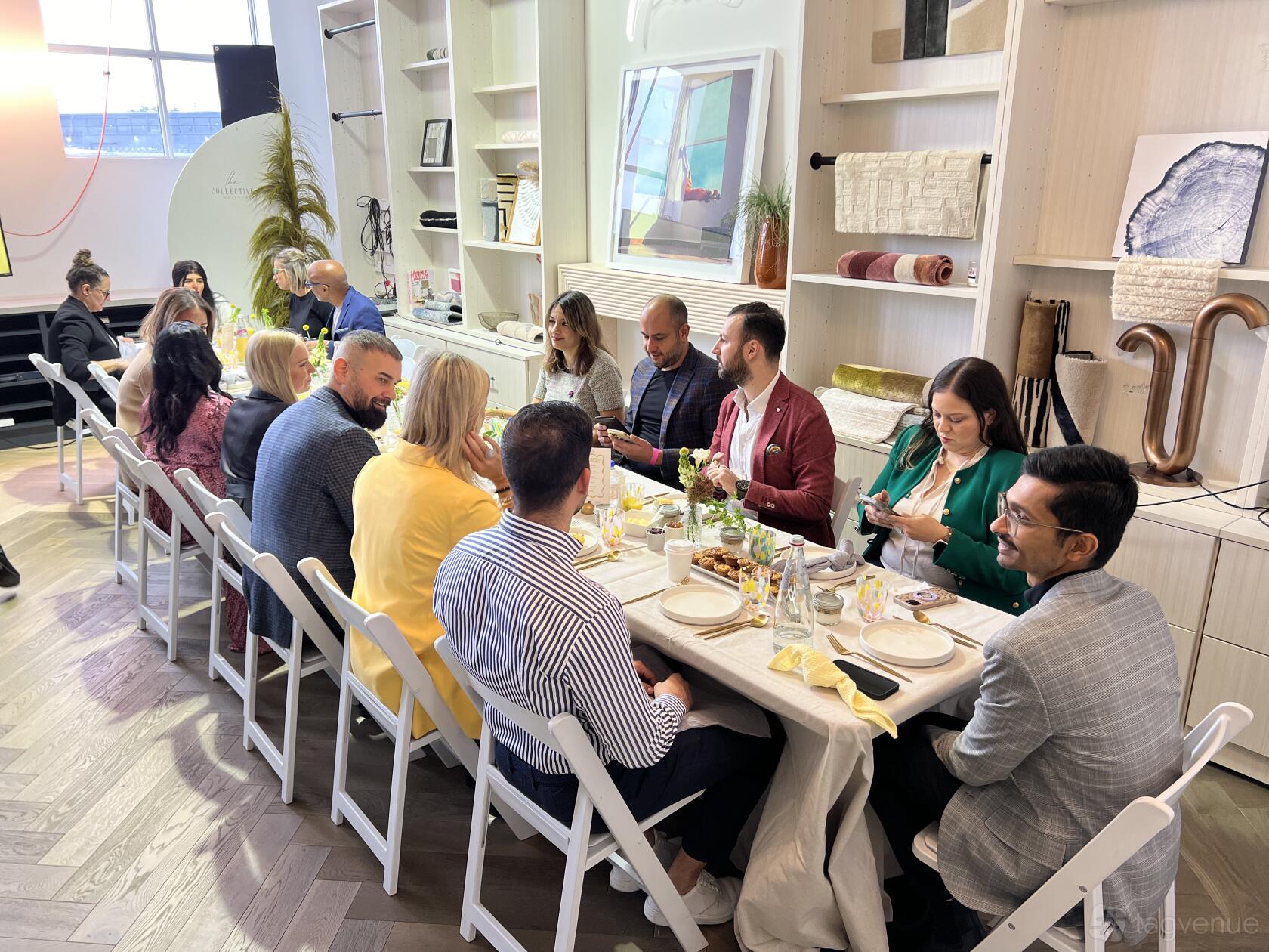 A function room with a long dining table, white chairs, and built-in shelves at The Collective Workspace.