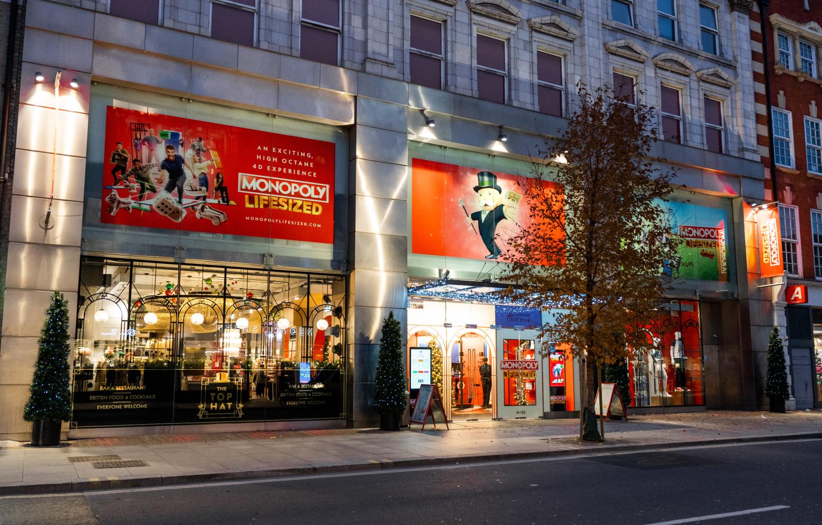 A versatile event space with illuminated signage, floor-to-ceiling windows, and MONOPOLY-themed banners at MONOPOLY LIFESIZED.