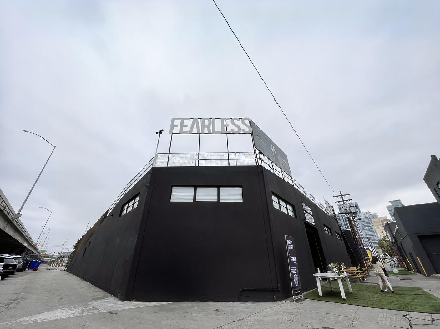 A church with a black exterior facade, rooftop FEARLESS sign, and outdoor benches at Fearless LA.