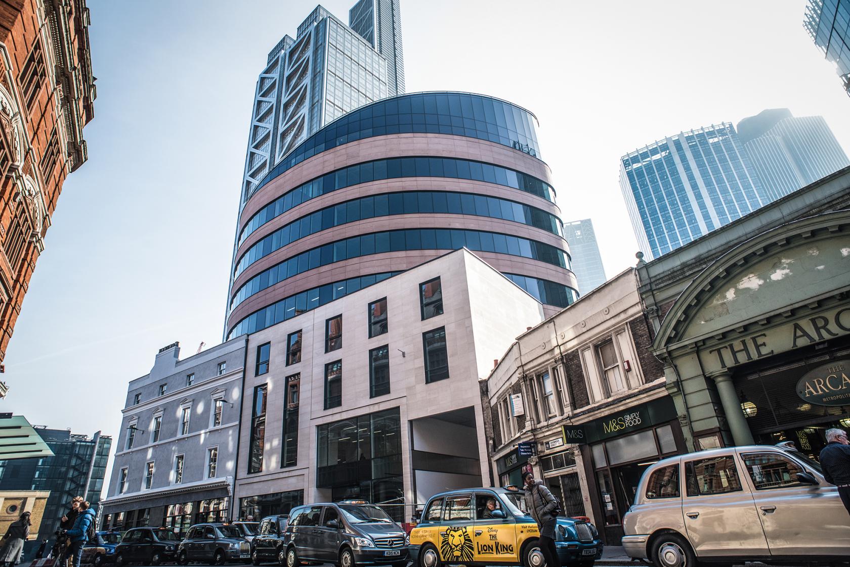 A coworking space in a modern curved glass building surrounded by city streets at Uncommon Liverpool Street.