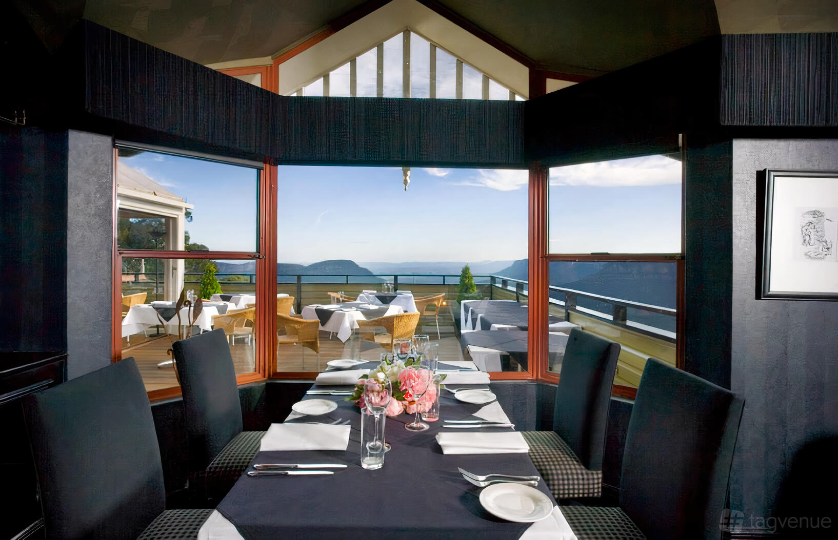 A dining room with floor-to-ceiling windows, black tablecloths, and mountain views at Echoes Boutique Hotel & Restaurant.