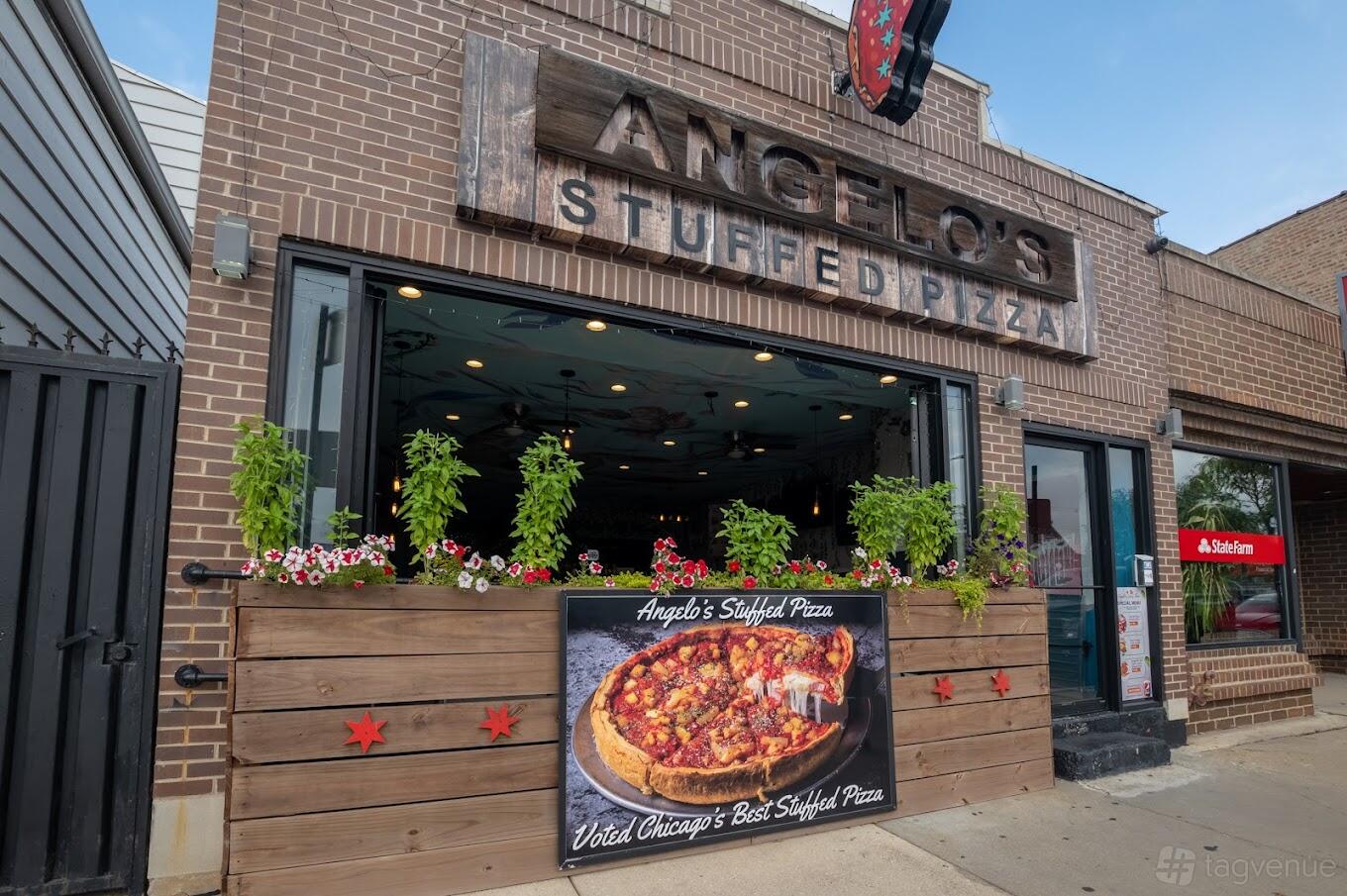 A restaurant with an open facade, hanging string lights, and planter boxes with flowers at Angelo's Stuffed Pizza.