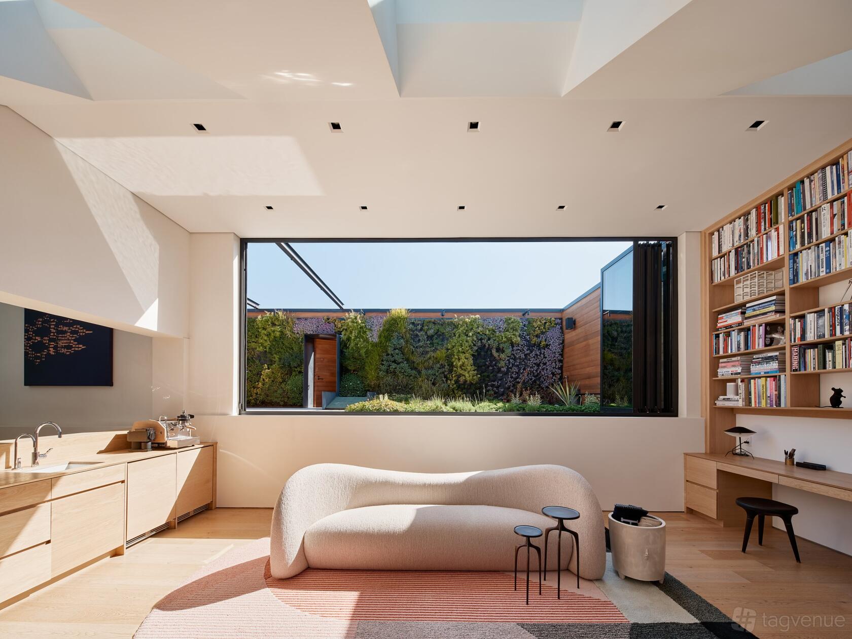 An event venue lounge with built-in bookshelves, a curving sofa, a large picture window and garden view at Four One Nine.