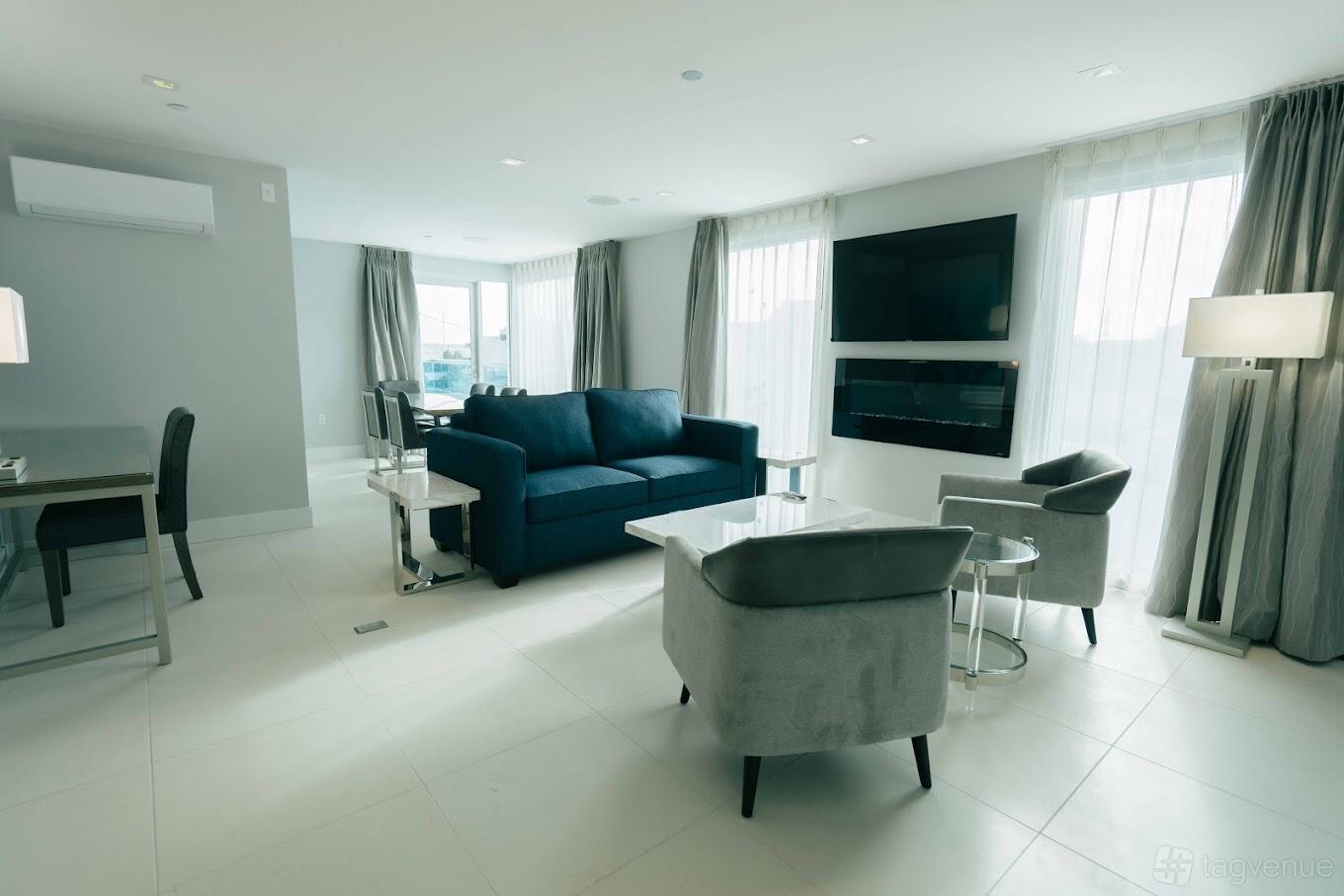 A meeting room with floor-to-ceiling windows, grey seating, and a wall-mounted TV at H2O Hermosa.
