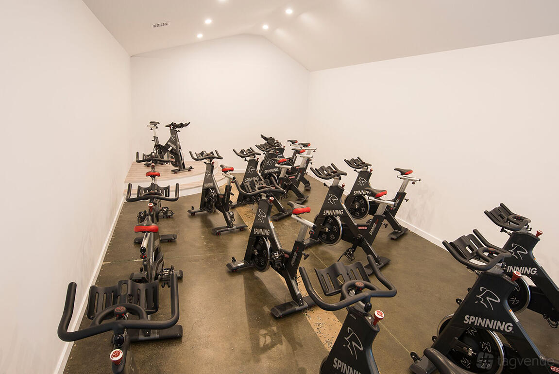 A film studio room with stationary spin bikes on polished concrete floors and white walls at All For One Yarraville.