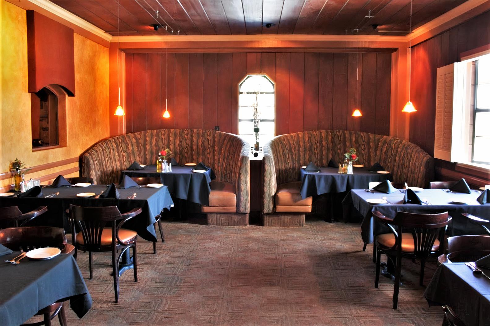 A restaurant with curved upholstered booths, wooden paneling, and pendant lighting at Spin A Yarn Steakhouse.