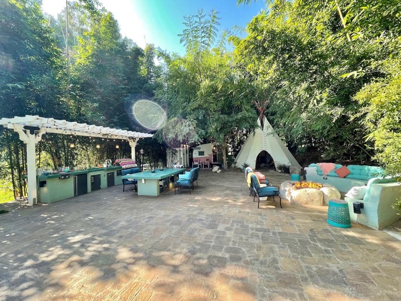 An outdoor event venue with a built-in bar, long dining tables, a teepee tent, and lounge seating at Wishing Well Mini Ranch.