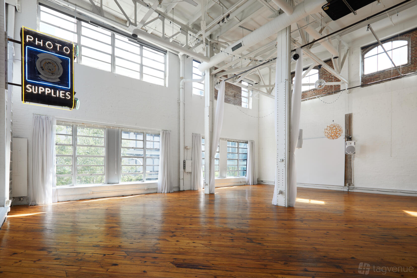 A photo studio with large industrial windows, white brick walls, and exposed beams at Power Plant Productions.
