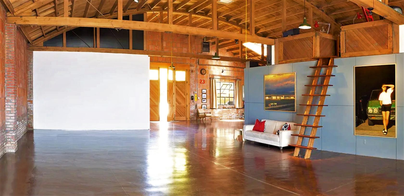 A spacious photo studio with polished concrete floors, exposed beams, a loft ladder, and natural light at 30th Street Garage.
