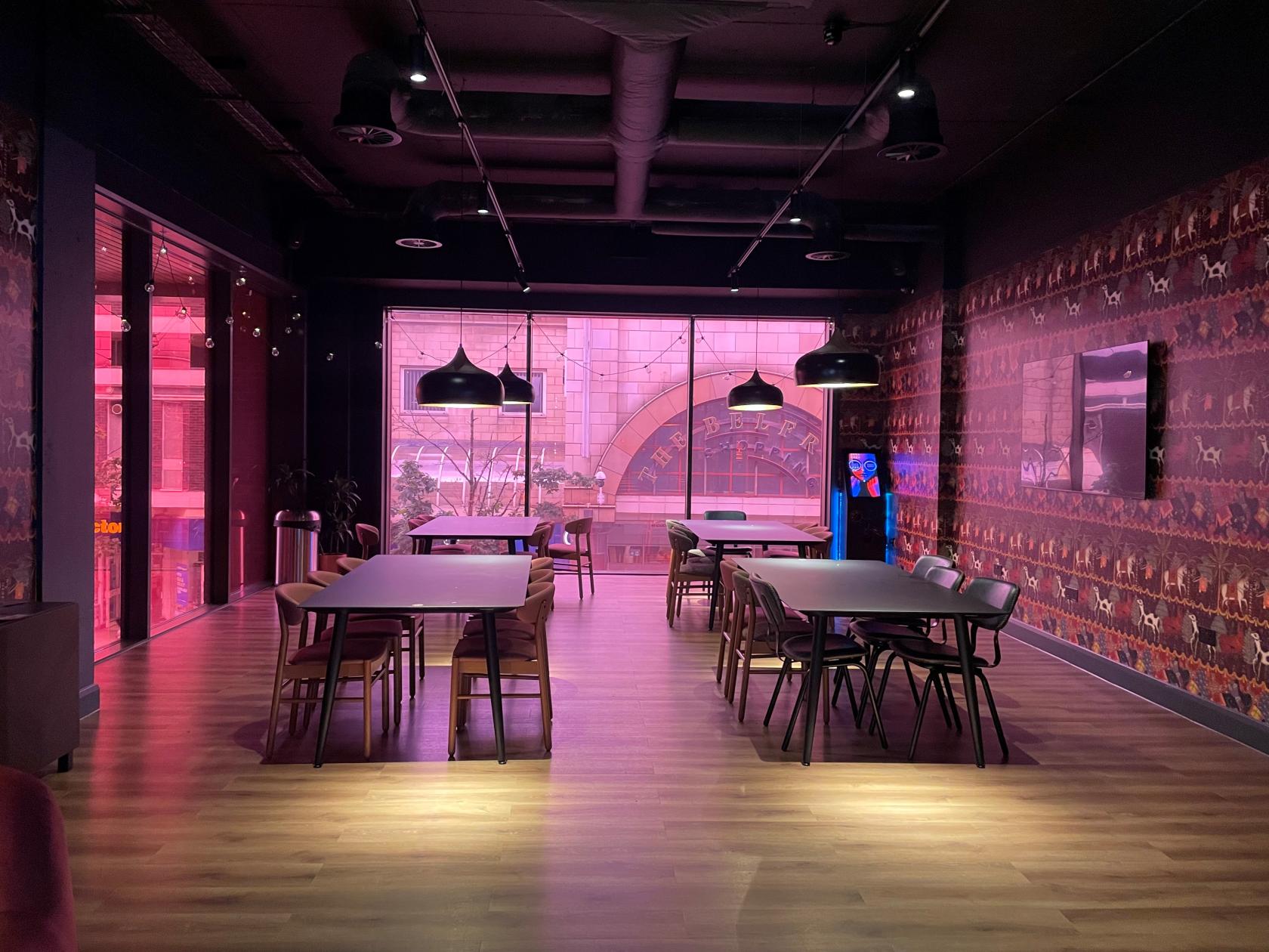 A cinema lounge with wooden floors, patterned wallpaper, modern pendant lights, and large windows at The Light Redhill.