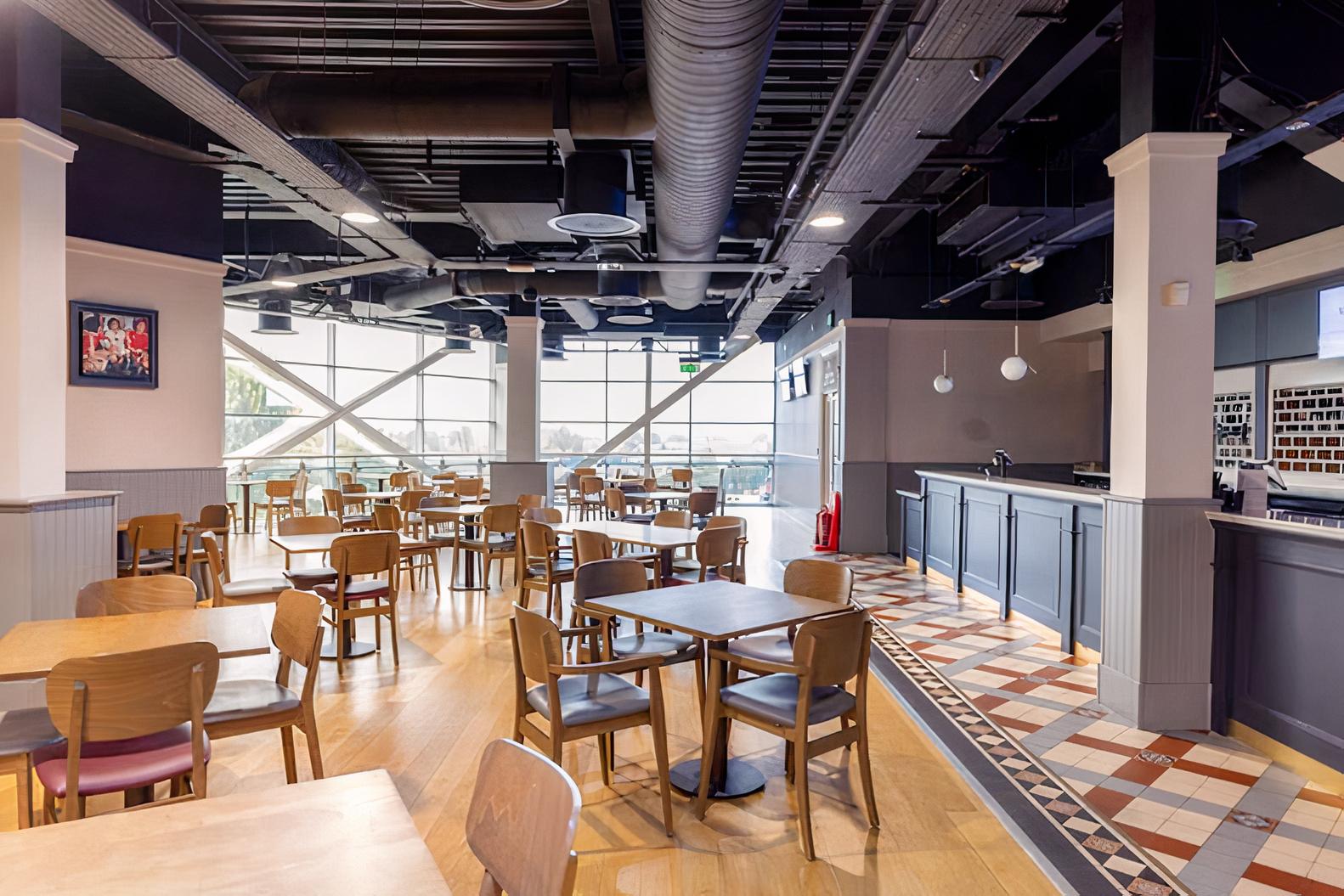 An event space with large windows, wooden tables and chairs, and a patterned tile floor at Villa Park.