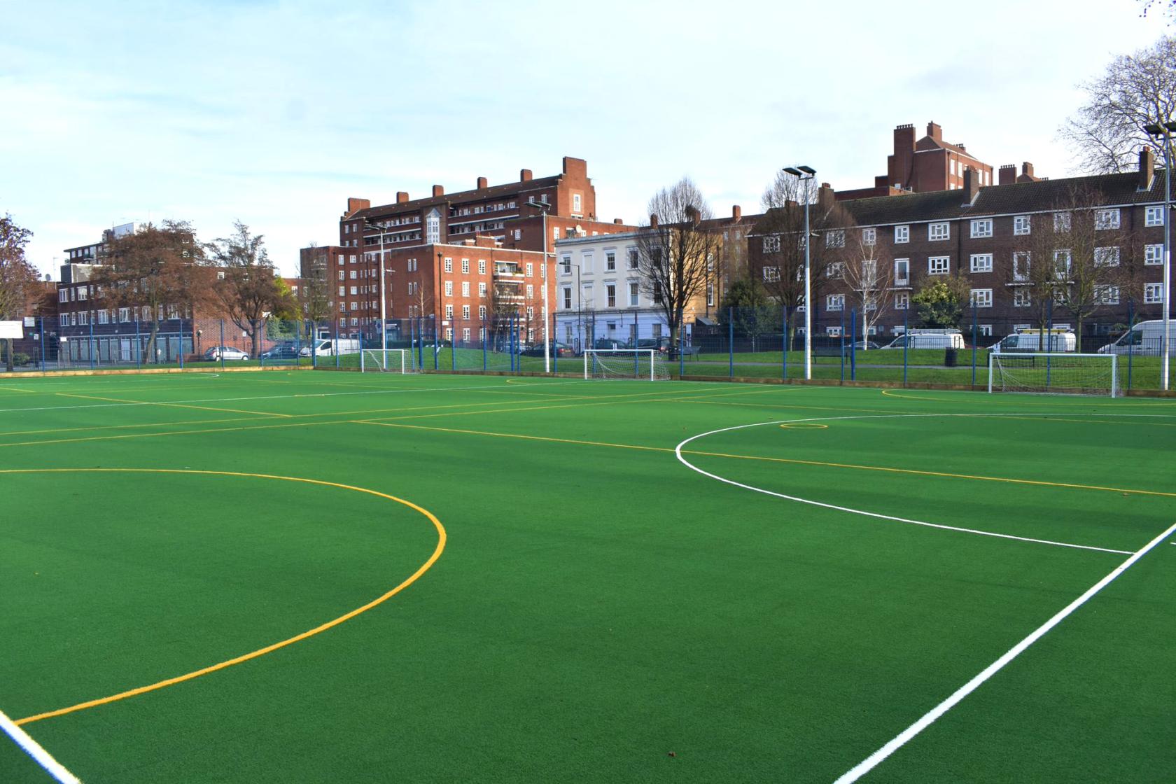 An outdoor sports field with marked astroturf pitches and fenced boundaries at Castlehaven Community Centre & Hub.