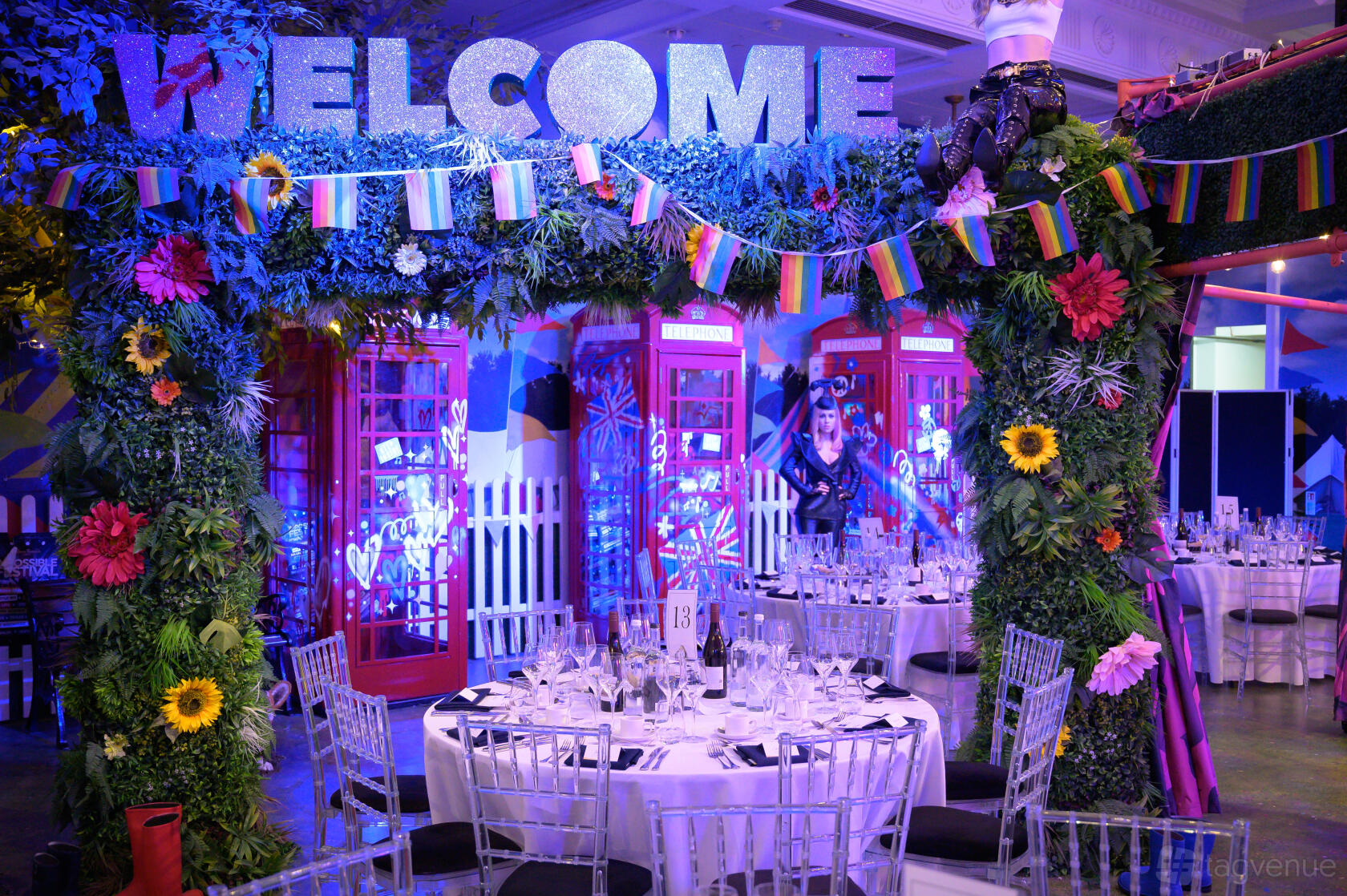 An event space with London phone booths, vibrant artificial flowers, and round tables with silver chairs at Madame Tussauds.