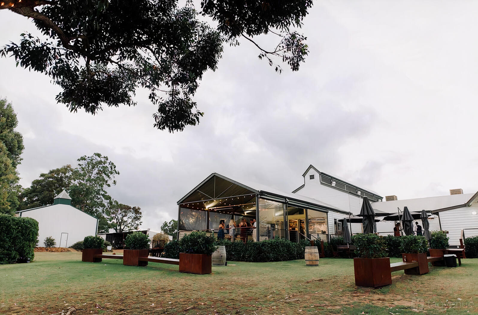 A restaurant with a covered outdoor dining area, string lights, and wine barrels at Rustico At Hay Shed Hill.