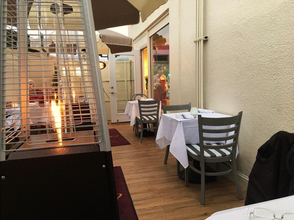 A terrace with outdoor tables, white tablecloths, and a patio heater at French Bistro ChouChou.