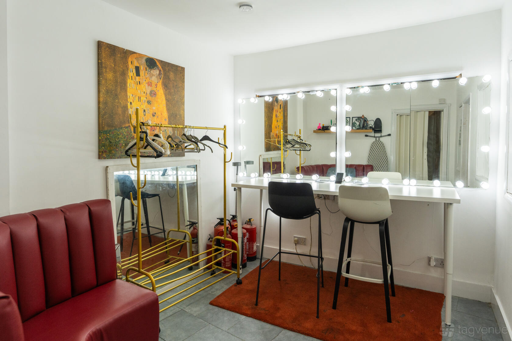 A photo studio with a makeup station featuring a large mirror with lights, dressing area, and seating at 6 Degrees studio.