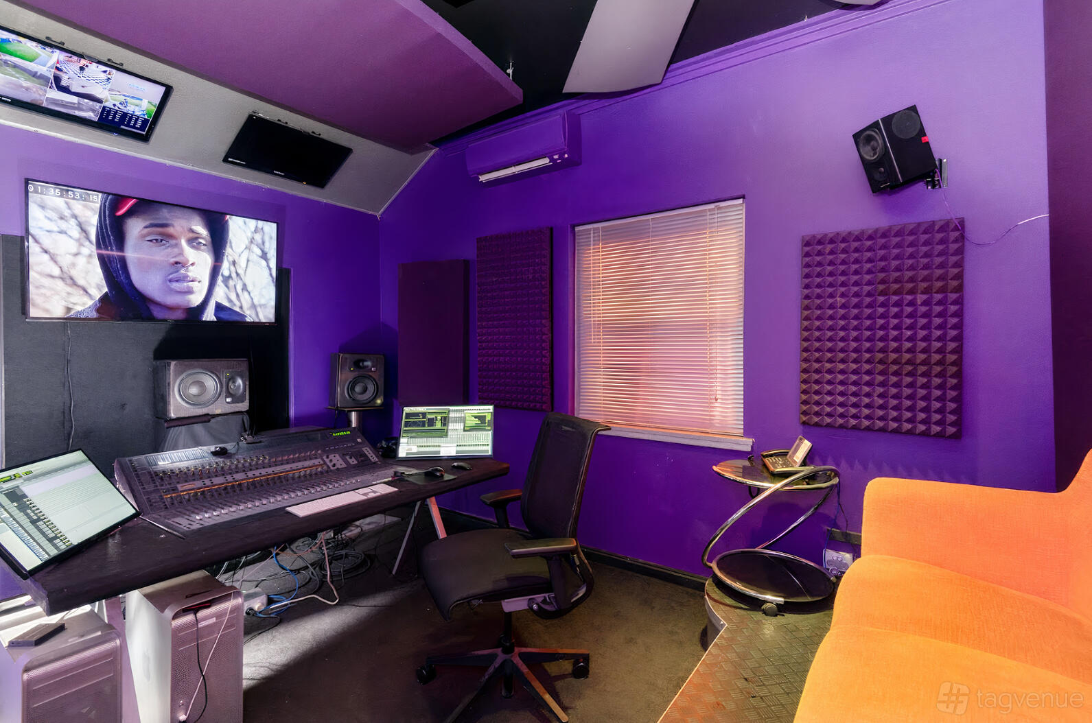 A film studio with soundproofed purple walls, mixing desk, monitors, and orange seating at Pow Wow Studios.
