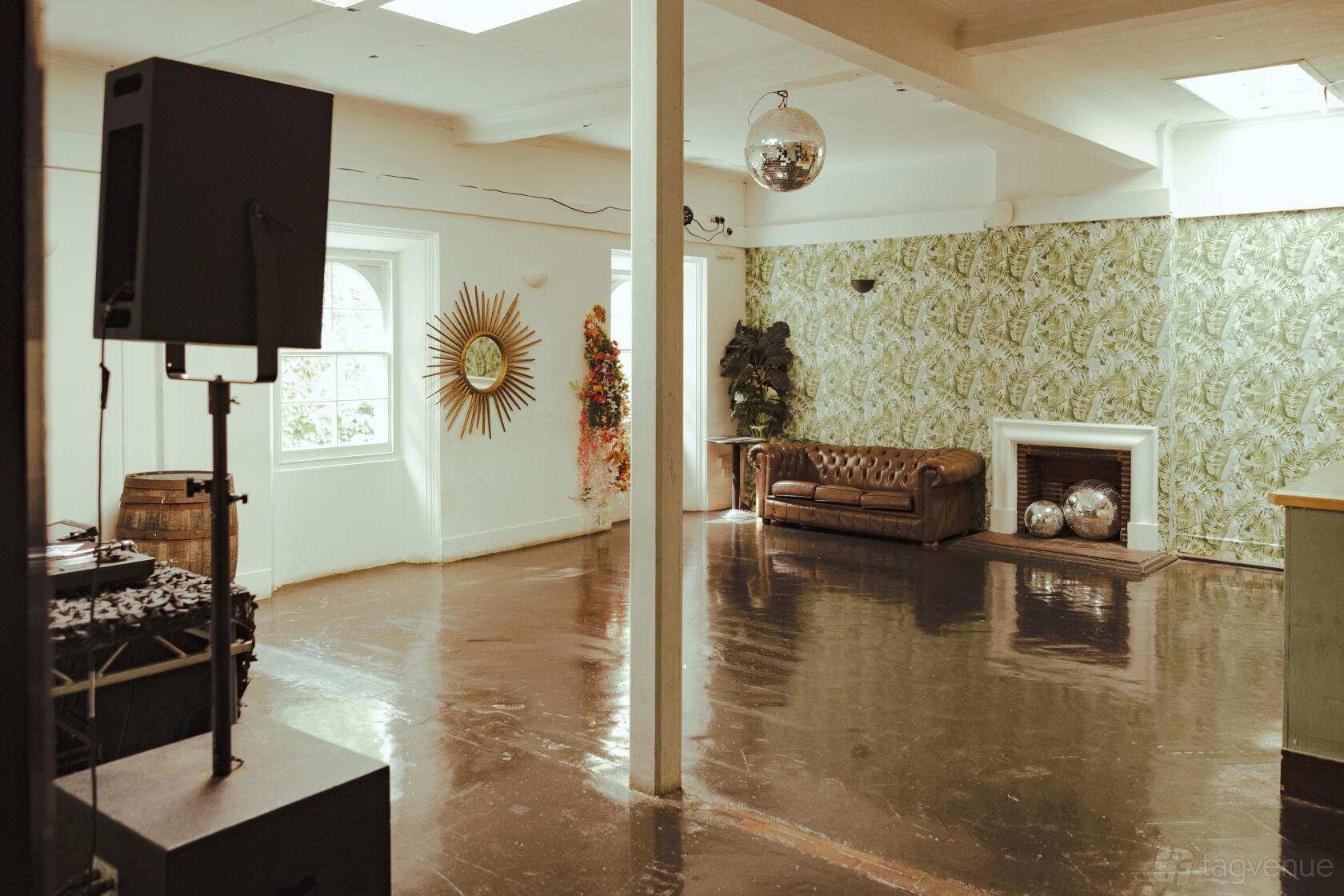 A nightclub terrace with a leather sofa, fireplace, retro wallpaper, and disco balls at 93 Feet East.