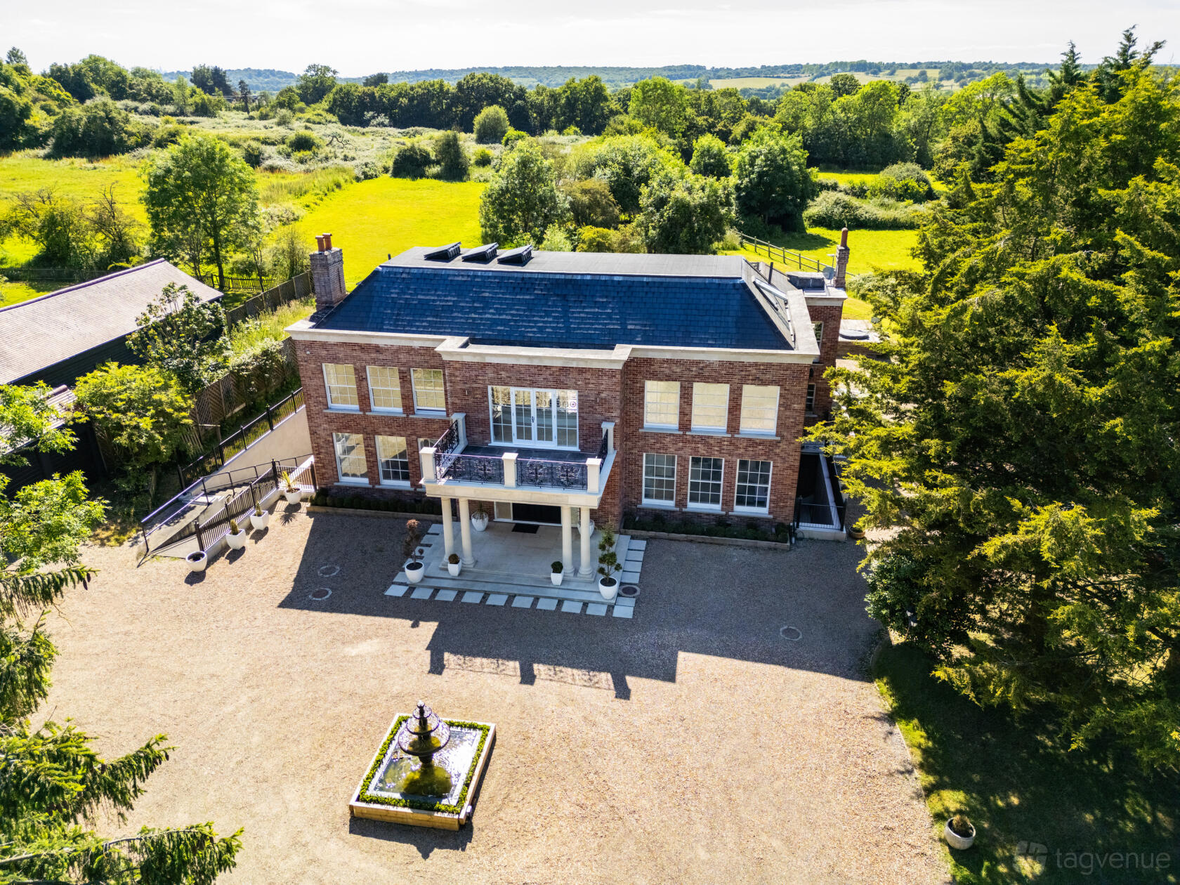 A country house with a brick exterior, large windows, and a circular driveway at The Essex Mansion & Spa, Chigwell.