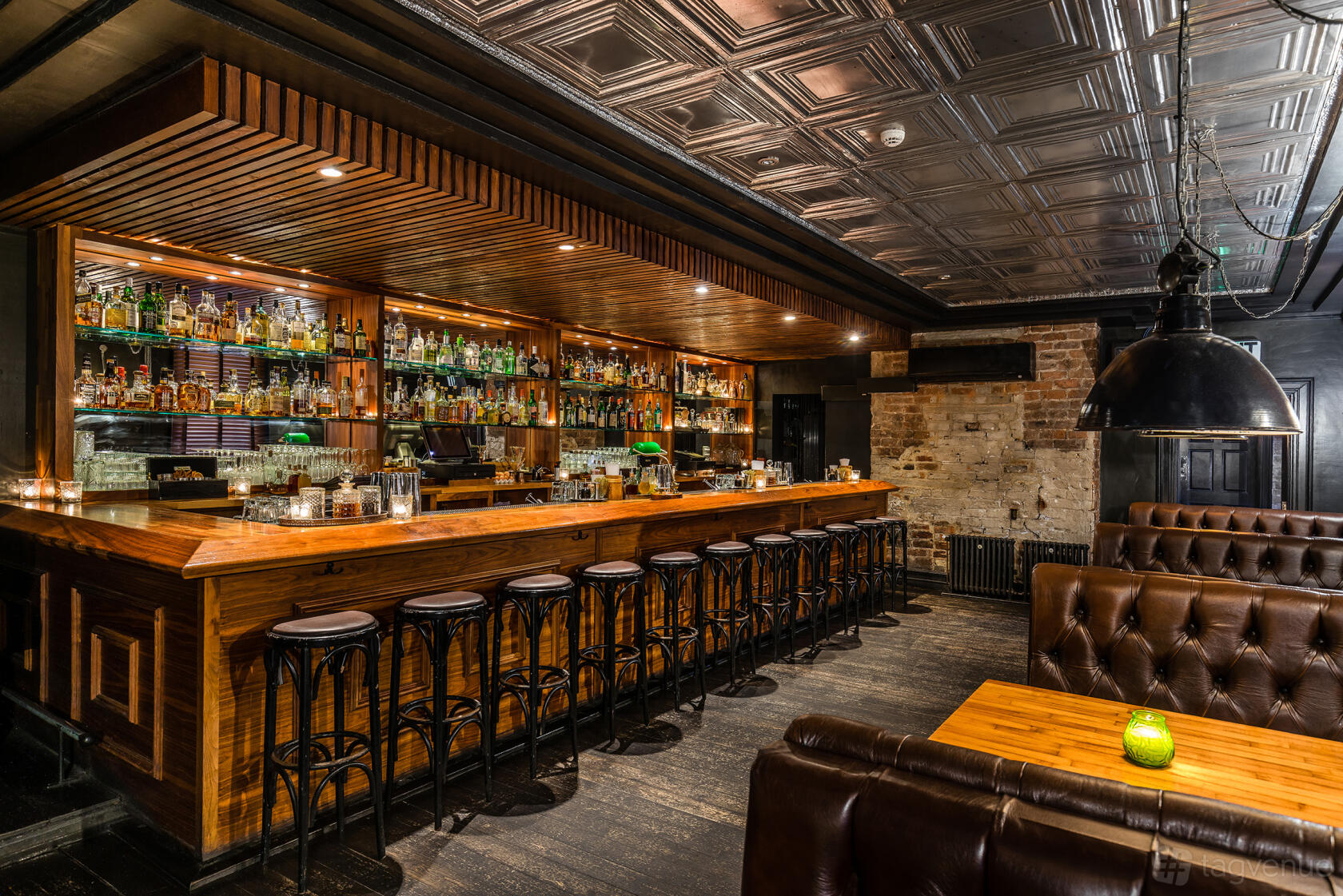 A cocktail bar with a long wooden counter, stocked back bar shelves, and brown leather seating at 81 LTD.