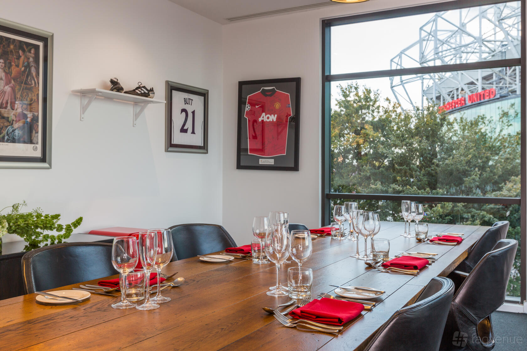 A meeting room with a long wooden table, glassware, sports memorabilia, and large window overlooking Hotel Football.
