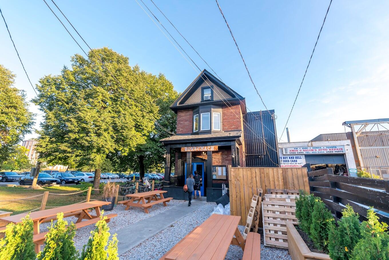 A brewery with outdoor picnic tables, gravel walkways, and a red brick house facade at Rorschach Brewing Co.