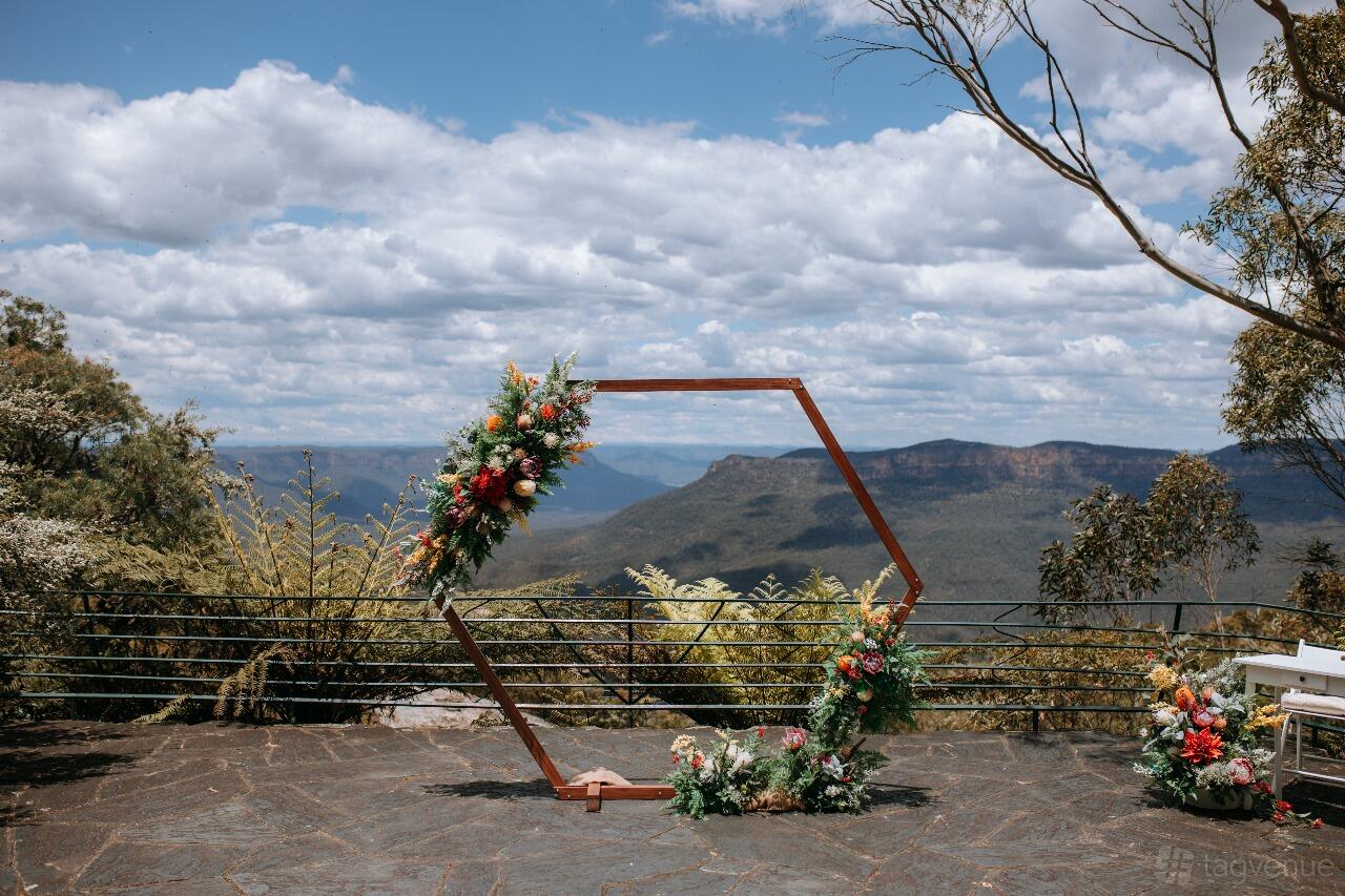 An open air venue with a hexagonal floral arch and mountain views at Blue Mountains Weddings.