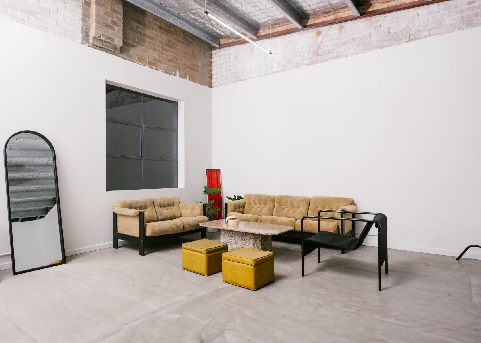 A photo studio with beige sofas, a terrazzo coffee table, and exposed brick walls at UNO STUDIOS.