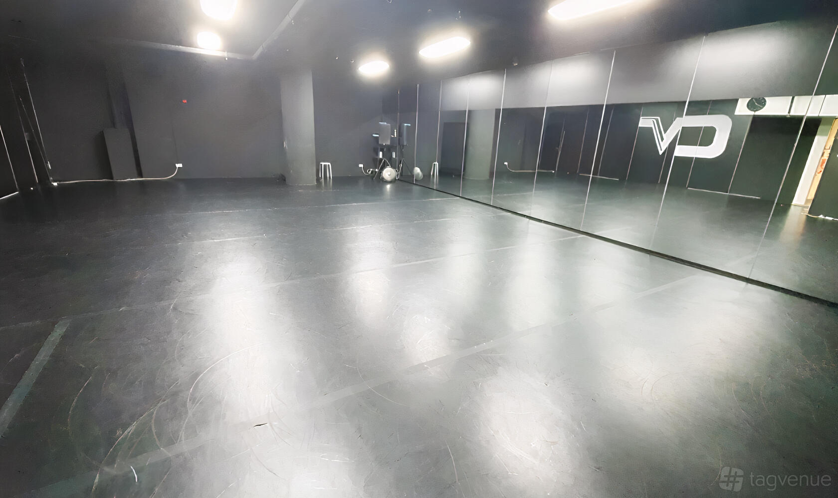 A dance studio with dark flooring, mirrored walls, and ceiling lights at Converge Studios Dhoby Ghaut MRT.
