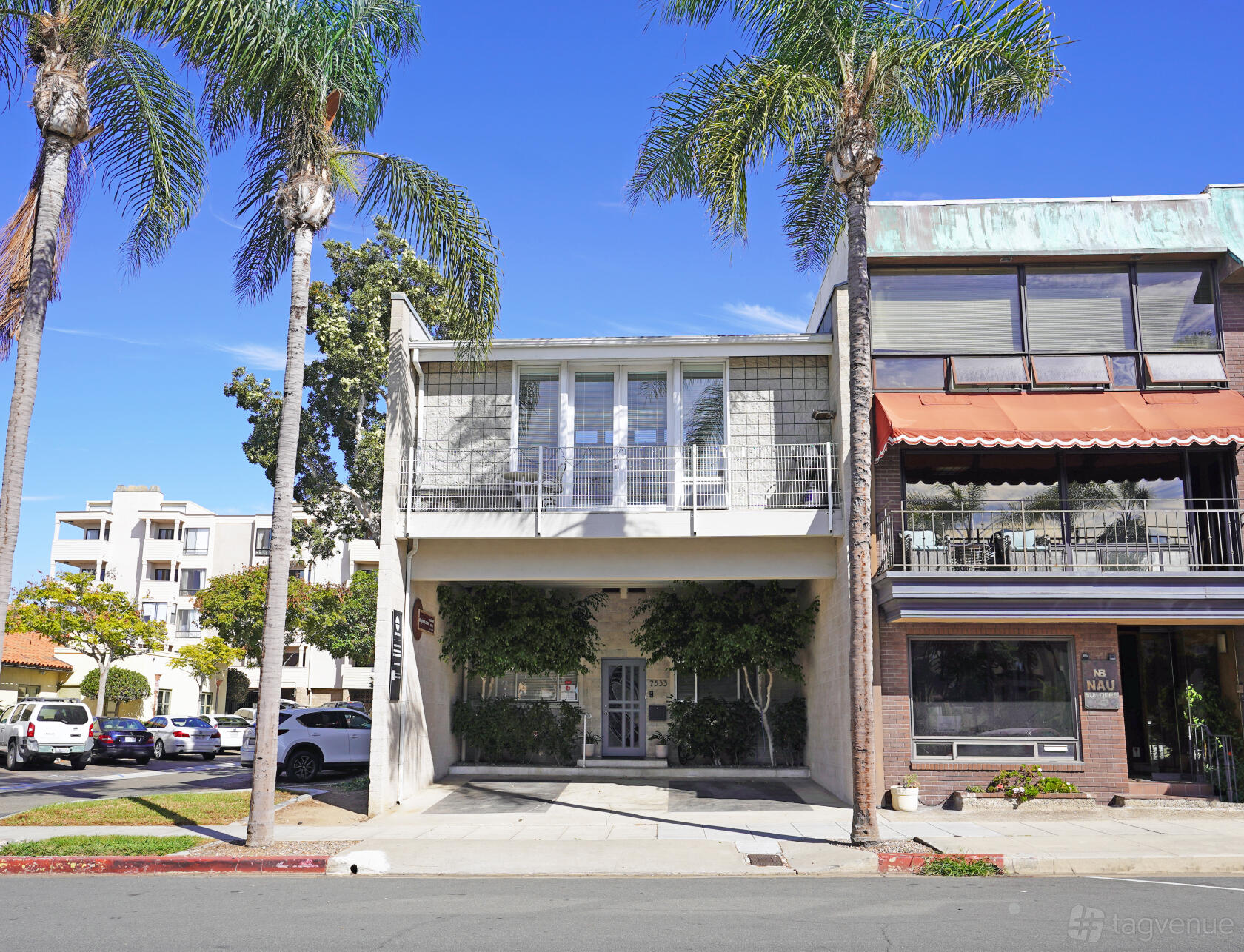 A film and photo studio with a modern facade, large windows, and palm trees at REV Studio.