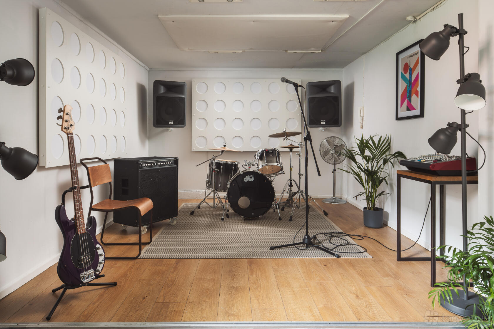 A rehearsal studio with a drum kit, amps, microphone, guitar, and acoustic panels at Factory Studios.