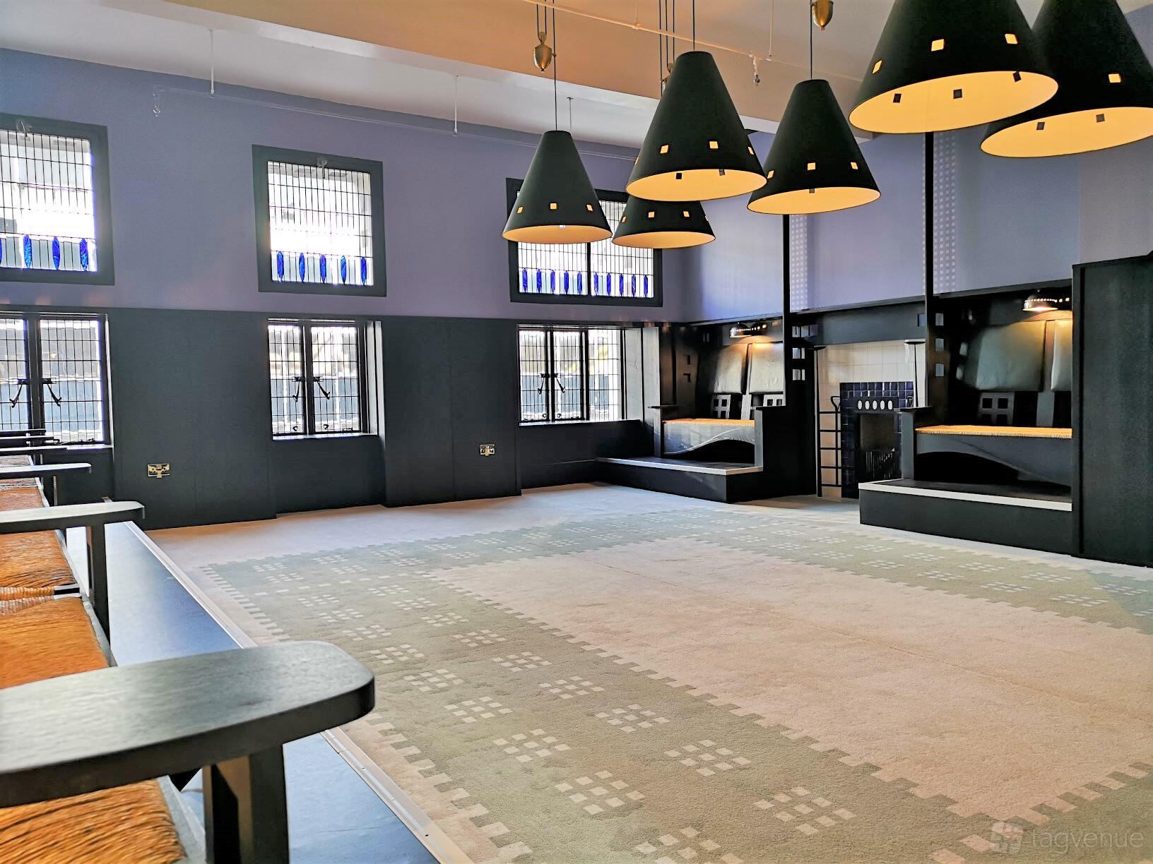 A historic dining room with tall stained glass windows, pendant lights, and built-in bench seating at Mackintosh at the Willow.