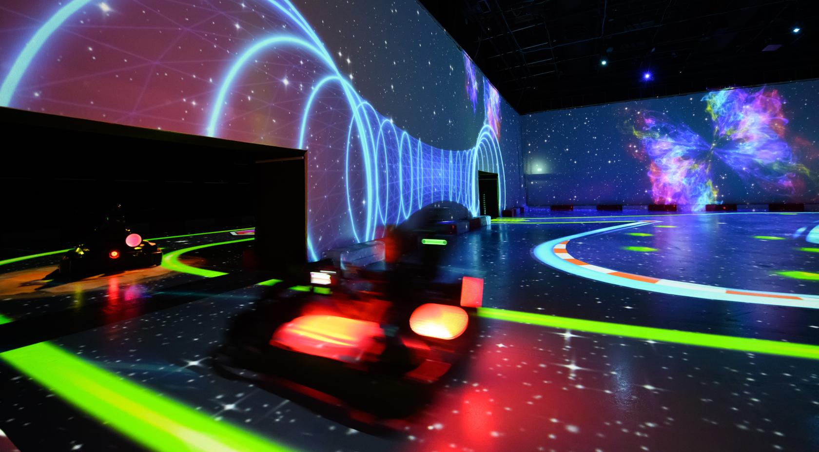 An event venue with immersive neon race tracks and glowing wall projections at Chaos Karts Manchester.