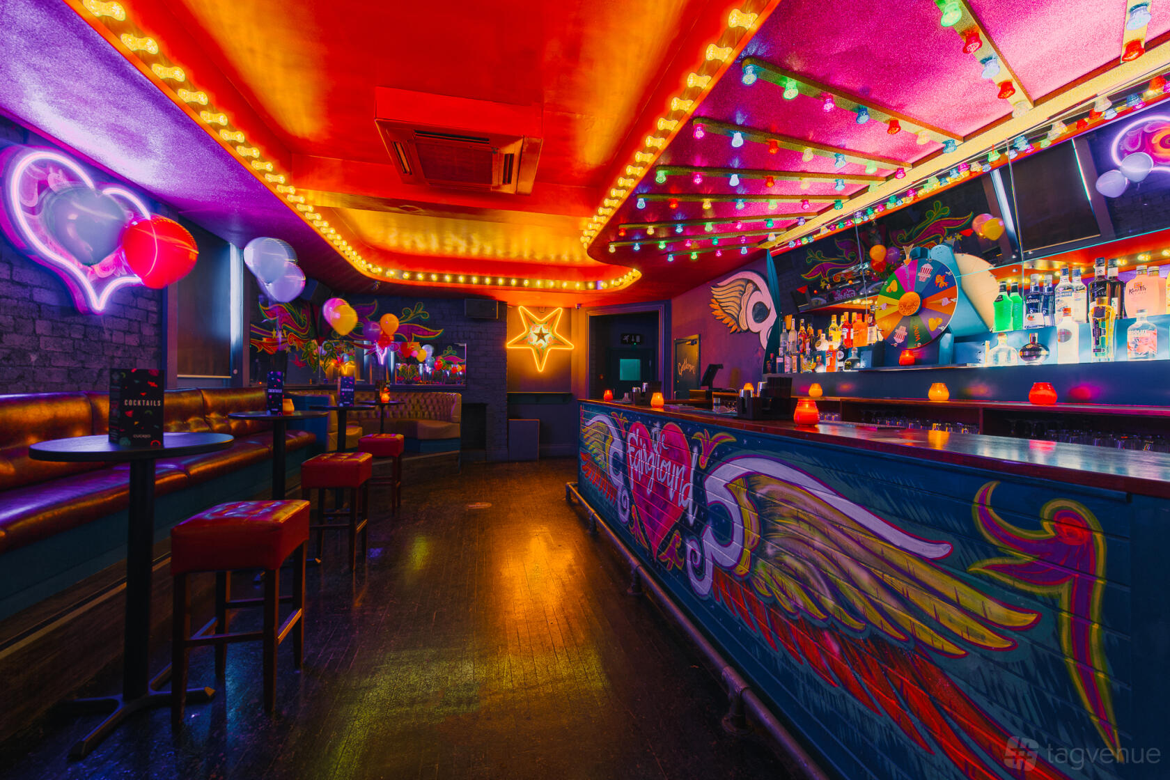 An event space in a bar with neon signs, colorful murals, and string lights above the bar at Cuckoo.
