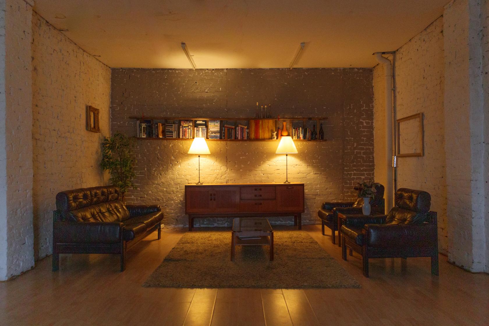 A photo studio with exposed brick walls, leather sofas, and warm lamp lighting at Stand Out Shots.