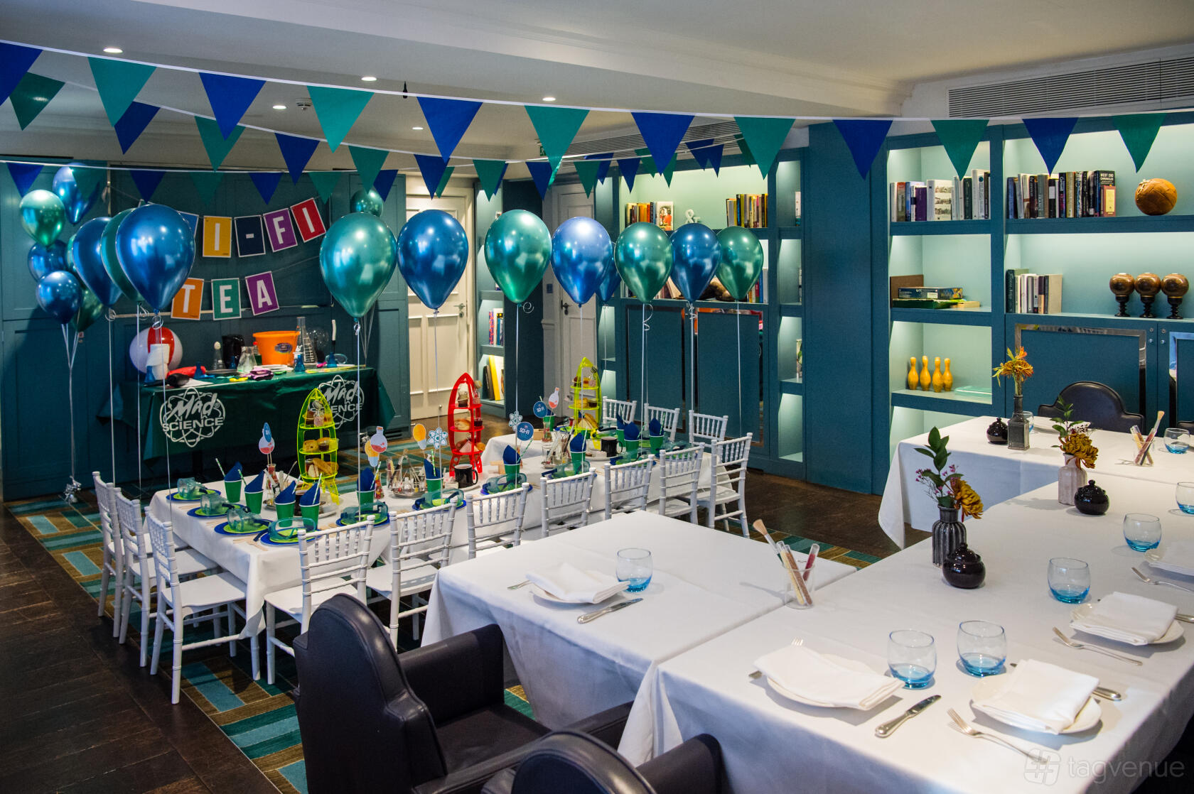 A hotel function room decorated with blue balloons, party banners, and a kids' table at The Ampersand Hotel.